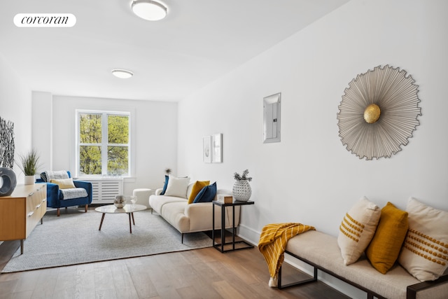 living area with electric panel, visible vents, and wood finished floors