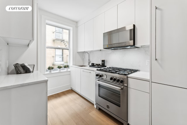 kitchen featuring a sink, stainless steel appliances, light wood-type flooring, and white cabinetry