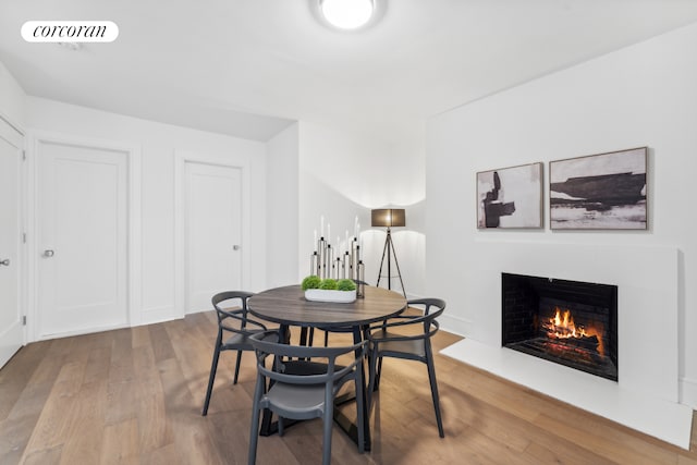 dining space with wood finished floors, visible vents, and a warm lit fireplace