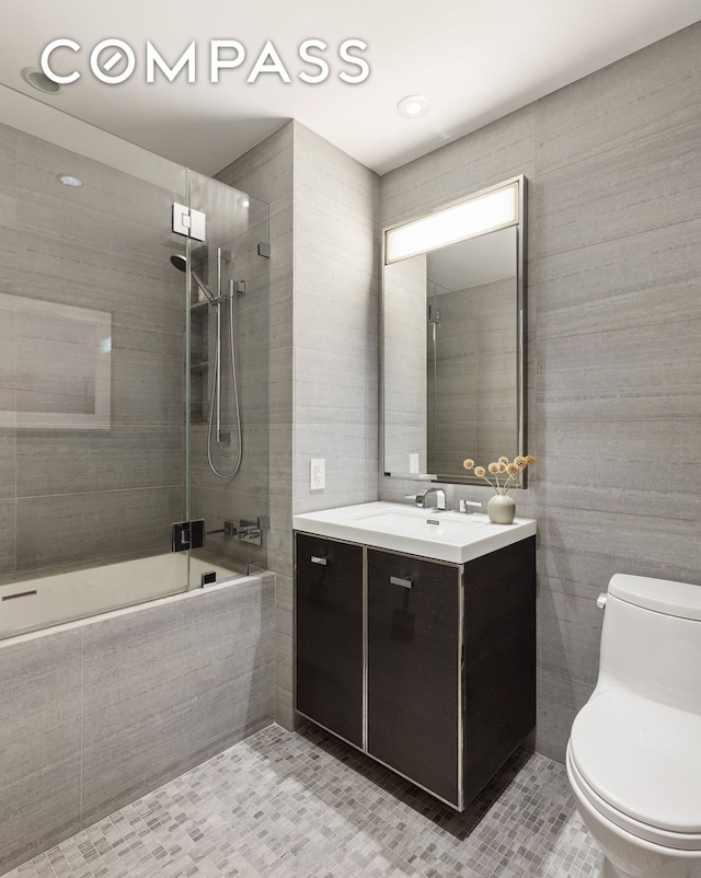 full bath featuring tile patterned flooring, tile walls, toilet, vanity, and tiled shower / bath