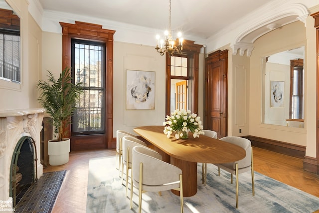 dining room featuring baseboards, a fireplace with flush hearth, a notable chandelier, and ornamental molding