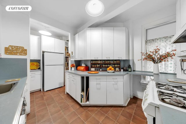 kitchen with light tile patterned flooring, white appliances, sink, and white cabinets