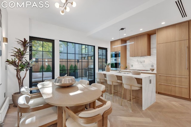 dining area with sink, a notable chandelier, and light parquet flooring