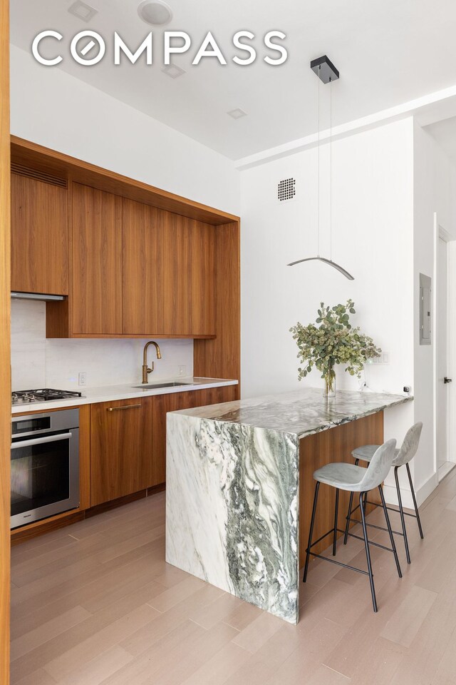 kitchen featuring appliances with stainless steel finishes, modern cabinets, a sink, and brown cabinets