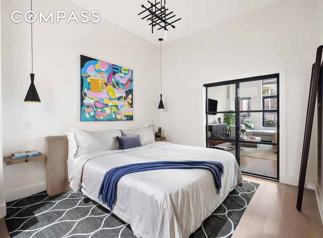 bedroom featuring access to outside, baseboards, and wood finished floors