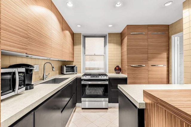 300 E 74th St Unit 3C, New York City, NY 10021 - kitchen with decorative backsplash, light countertops, appliances with stainless steel finishes, a sink, and light tile patterned floors
