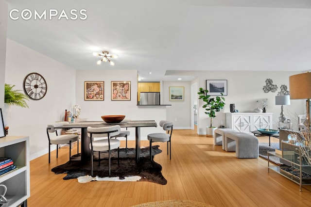 dining space featuring an inviting chandelier, light wood-style flooring, and baseboards