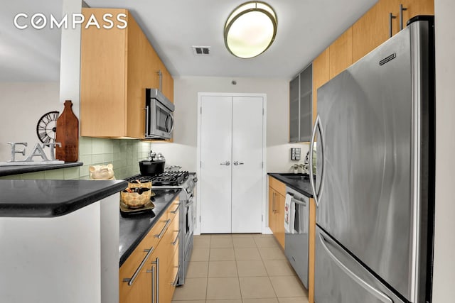 kitchen featuring stainless steel appliances, dark countertops, visible vents, and light tile patterned floors