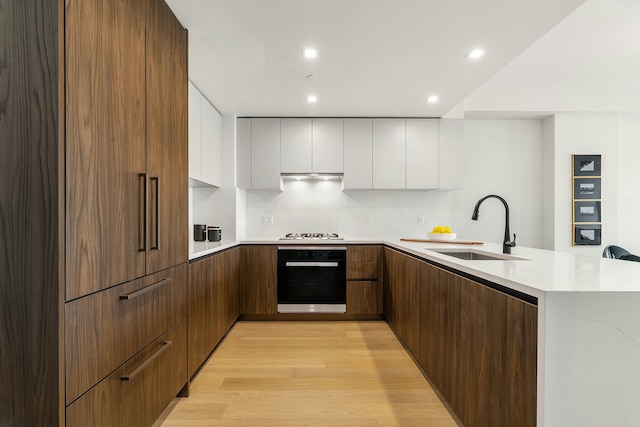 kitchen featuring black oven, white gas stovetop, white cabinets, modern cabinets, and a sink