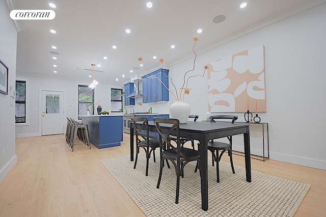 dining area with light wood-type flooring and crown molding