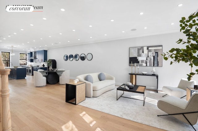 living area with ornamental molding, recessed lighting, visible vents, and light wood-style floors