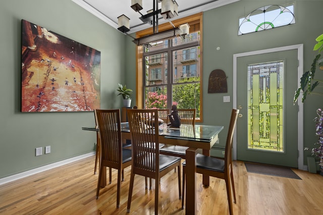 dining room with crown molding, a baseboard heating unit, and light wood-type flooring