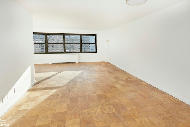 unfurnished room featuring radiator and baseboards