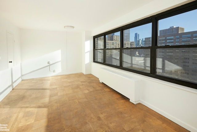 spare room with a city view, a healthy amount of sunlight, and baseboards