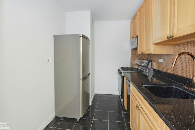 kitchen featuring gas stove, white microwave, light brown cabinets, freestanding refrigerator, and a sink