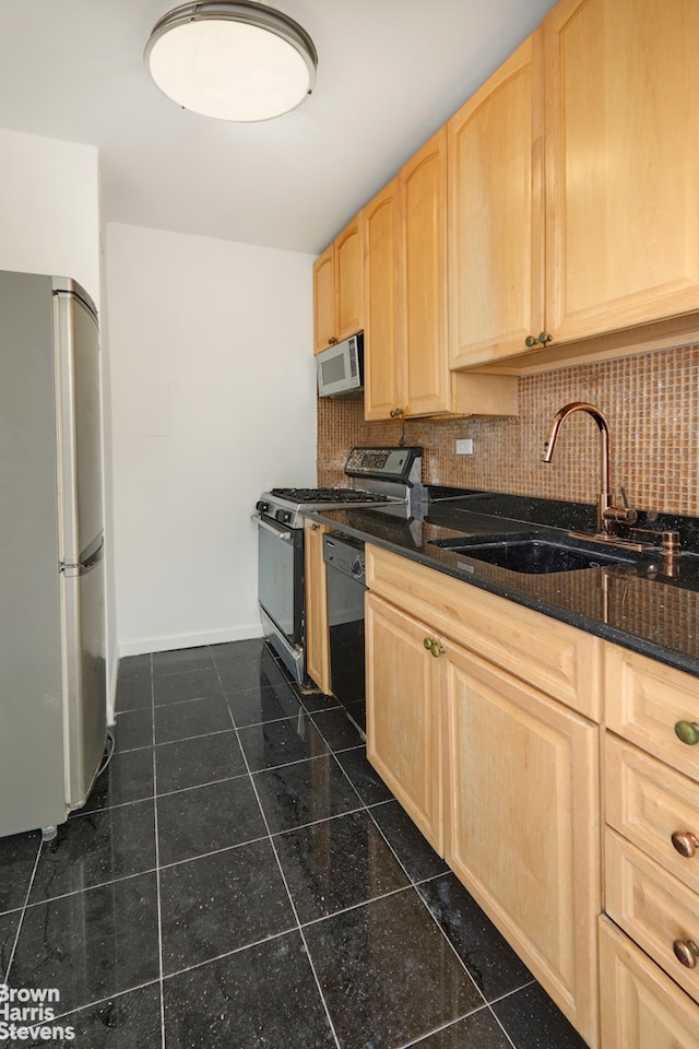 kitchen with light brown cabinetry, a sink, freestanding refrigerator, baseboards, and dishwasher