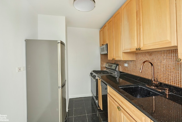 kitchen with light brown cabinets, dark stone counters, a sink, stainless steel appliances, and tasteful backsplash