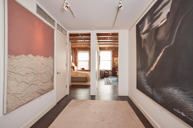 corridor featuring visible vents, baseboards, and dark wood-style floors