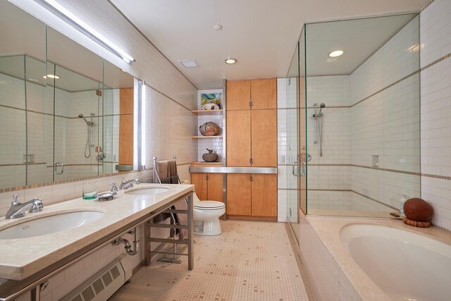 bathroom featuring toilet, a stall shower, tile walls, and a sink