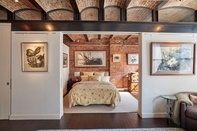 bedroom featuring wood finished floors, baseboards, brick wall, beamed ceiling, and brick ceiling