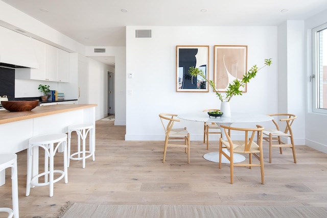 dining room featuring breakfast area, visible vents, baseboards, and light wood finished floors