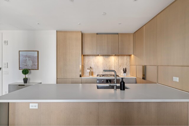 kitchen with light countertops, tasteful backsplash, a sink, and modern cabinets