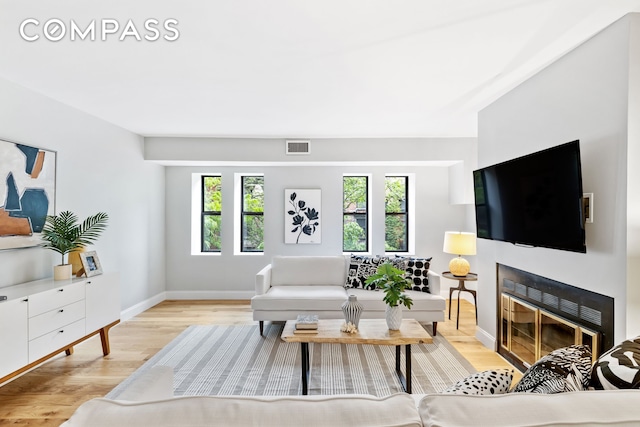 living area featuring plenty of natural light, visible vents, a fireplace, and wood finished floors