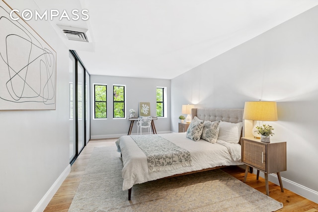 bedroom with light wood-type flooring, visible vents, and baseboards