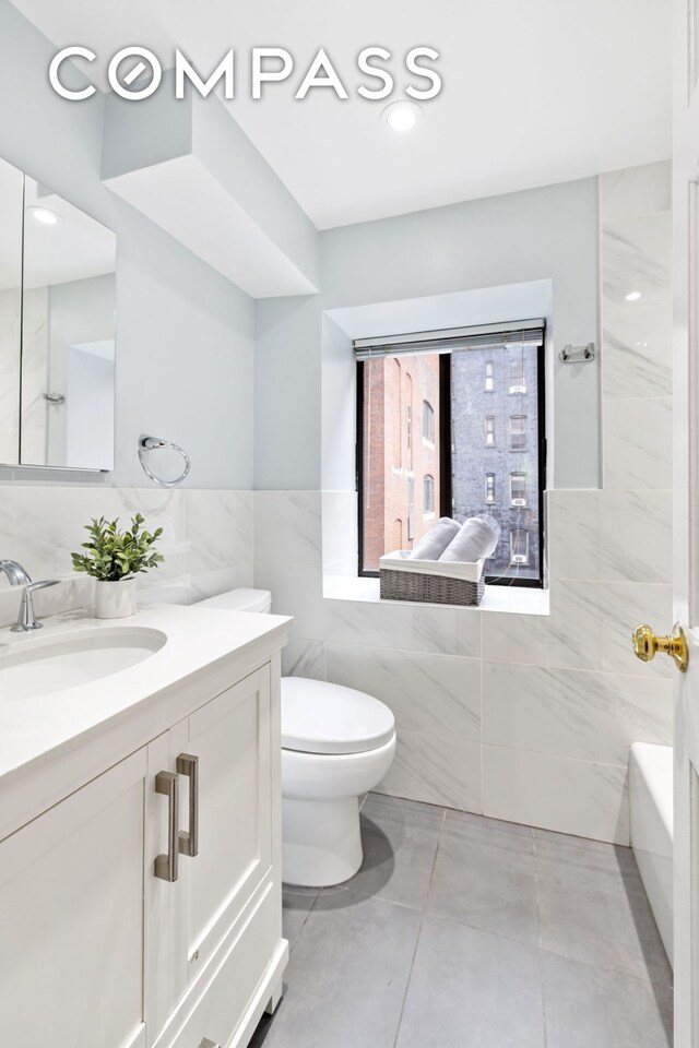 bathroom with toilet, tile walls, and vanity