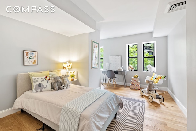 bedroom featuring wood finished floors, visible vents, and baseboards