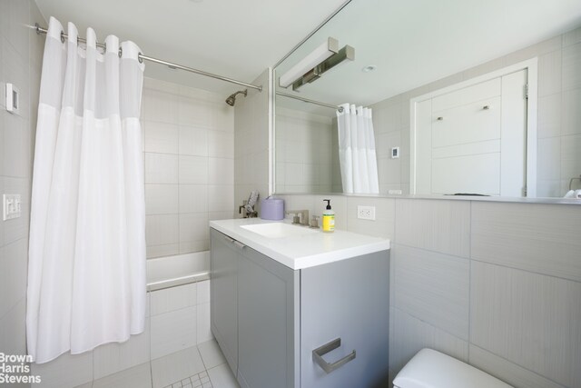 bathroom with vanity, tile walls, and a shower with shower door