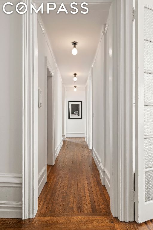 hallway with ornamental molding and dark hardwood / wood-style floors