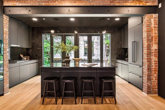 living room featuring brick wall, a fireplace, and light wood-type flooring