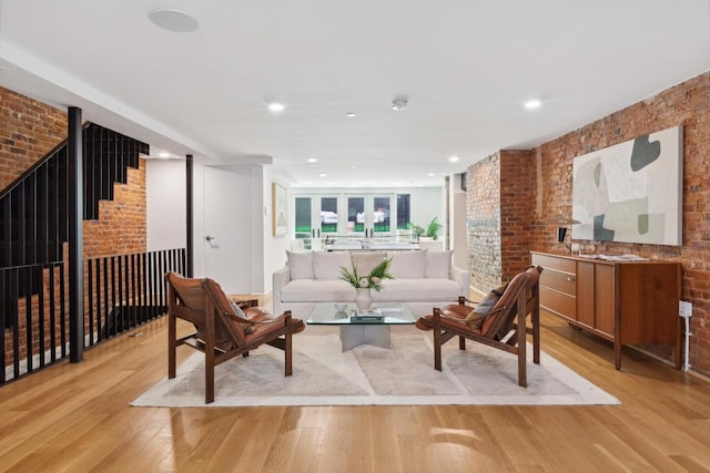 living room featuring brick wall and light hardwood / wood-style flooring