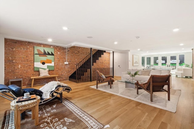 living room featuring hardwood / wood-style flooring, brick wall, and crown molding