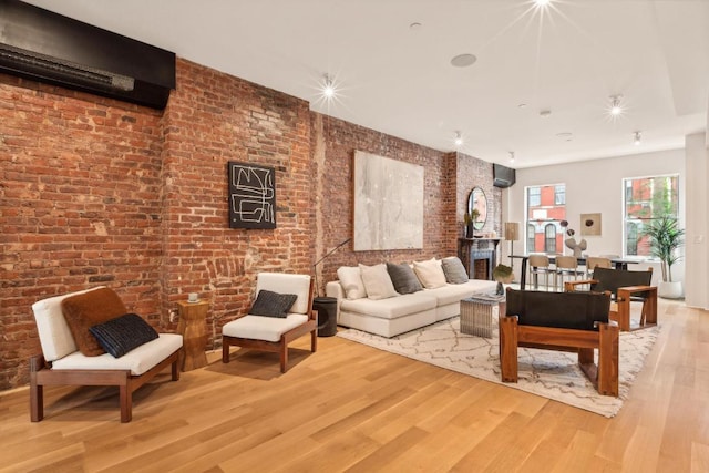 living room with hardwood / wood-style floors, a wall mounted AC, and brick wall