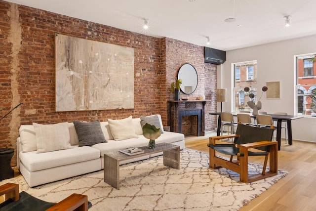 living room with hardwood / wood-style flooring and brick wall