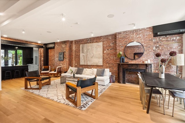 living room with hardwood / wood-style floors, a wood stove, beamed ceiling, and brick wall