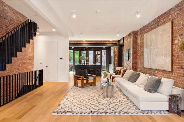 living room featuring wood-type flooring and brick wall