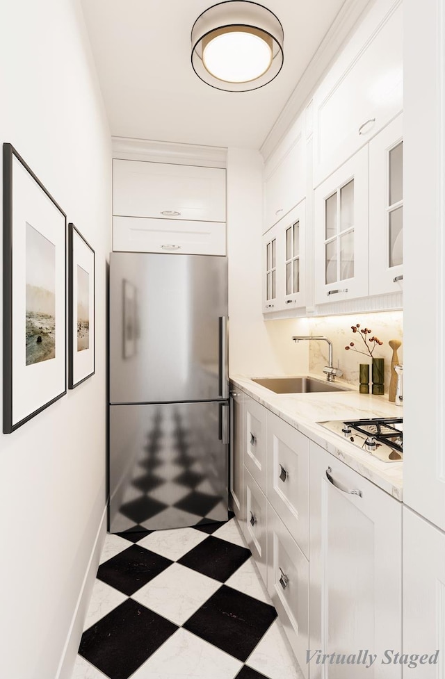 kitchen with white gas stovetop, a sink, tile patterned floors, stainless steel fridge, and glass insert cabinets