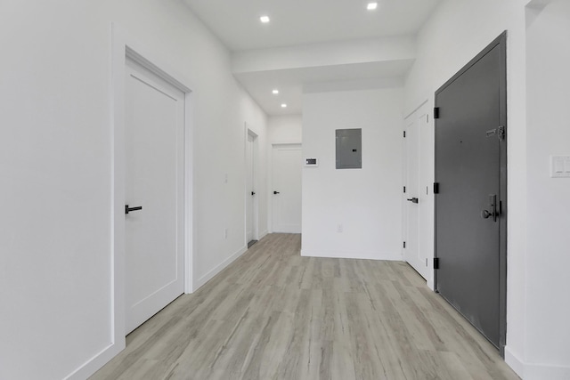 corridor featuring electric panel, light wood-style floors, recessed lighting, and baseboards