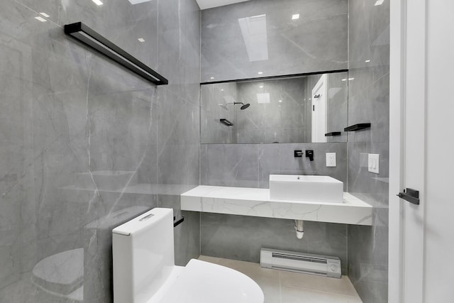 bathroom with a sink, toilet, and tile walls