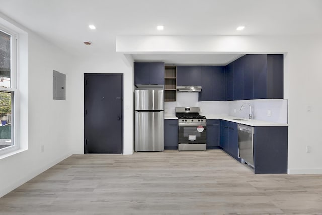 kitchen with a sink, under cabinet range hood, light countertops, appliances with stainless steel finishes, and open shelves