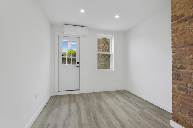 interior space with recessed lighting, light wood-type flooring, a wall mounted AC, and baseboards