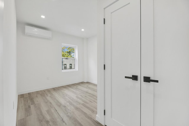 interior space with recessed lighting, a wall mounted air conditioner, baseboards, and wood finished floors