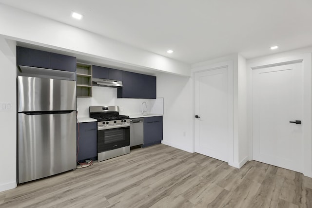 kitchen featuring under cabinet range hood, light countertops, light wood-style floors, stainless steel appliances, and a sink