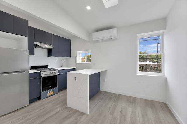 kitchen featuring a wall mounted AC, under cabinet range hood, tasteful backsplash, appliances with stainless steel finishes, and light wood finished floors