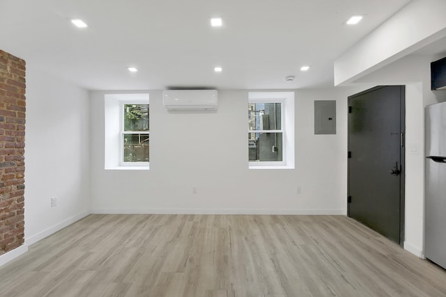 unfurnished room featuring light wood-style flooring, electric panel, baseboards, and a wall mounted air conditioner