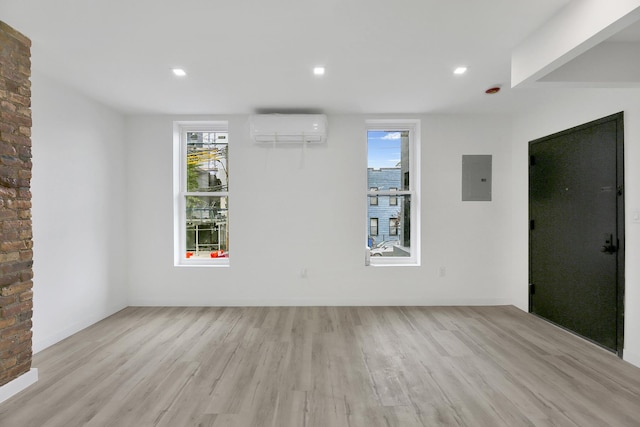 unfurnished room featuring electric panel, light wood finished floors, recessed lighting, and a wall unit AC