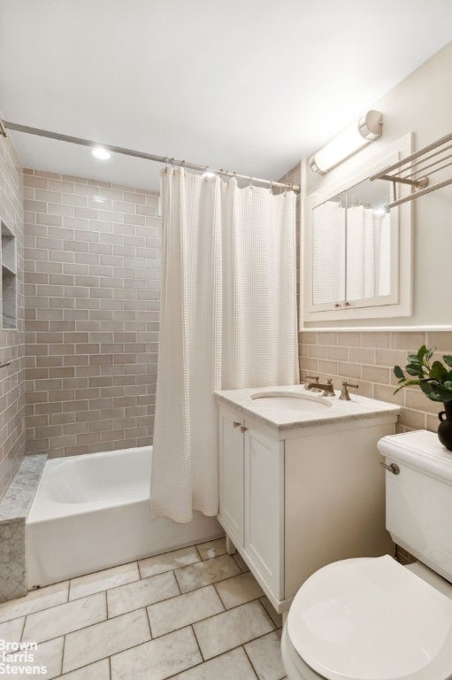 full bathroom with toilet, vanity, tile walls, tile patterned flooring, and shower / bath combo